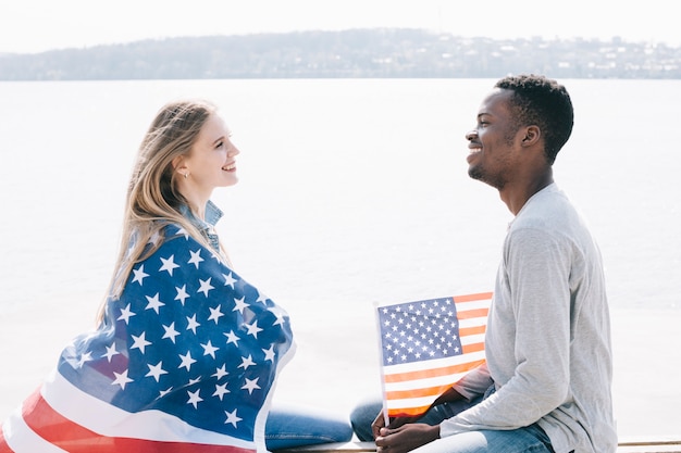 無料写真 海岸に座っていると一緒にアメリカの国旗を保持している笑顔若い人たち