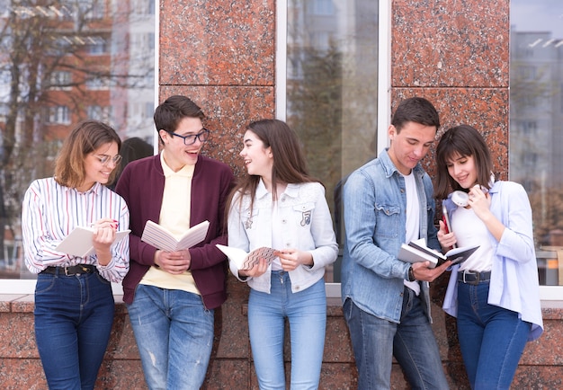 Young people standing with books and reading it discussing content 