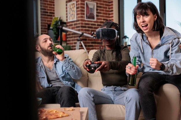 vr 안경을 사용하여 재미있는 집에서 비디오 게임을 하고 텔레비전에서 경쟁을 하는 젊은이들. 맥주병과 스낵, 3D 게임 파티로 여가 활동을 즐깁니다.
