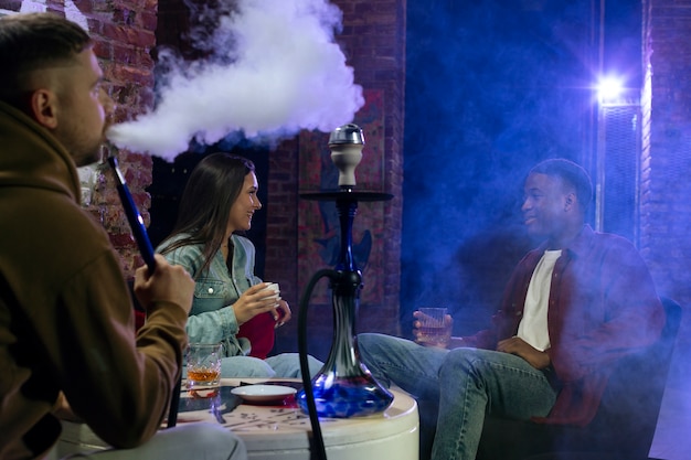 Young people vaping from a hookah in a bar