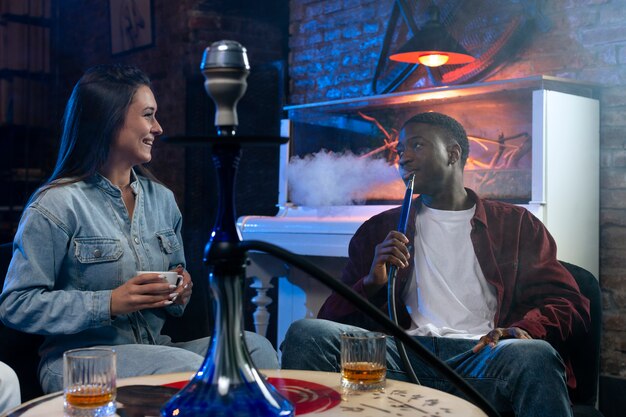 Young people vaping from a hookah in a bar