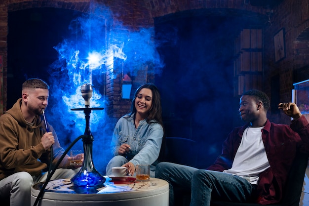 Free photo young people vaping from a hookah in a bar