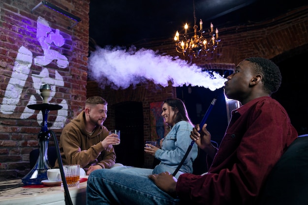 Young people vaping from a hookah in a bar