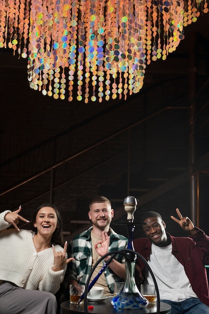 Free photo young people vaping from a hookah in a bar