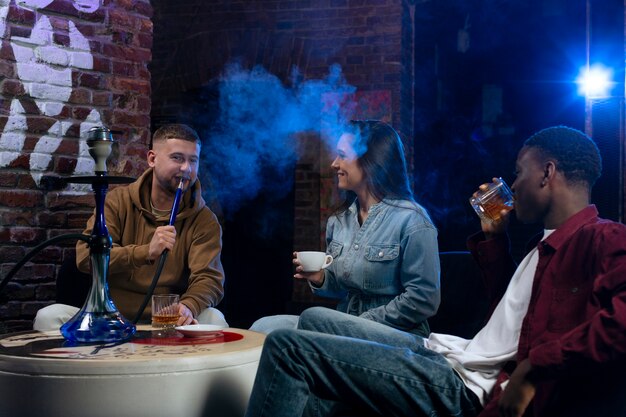 Young people vaping from a hookah in a bar