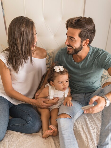 Young people with baby and smartphone looking at each other