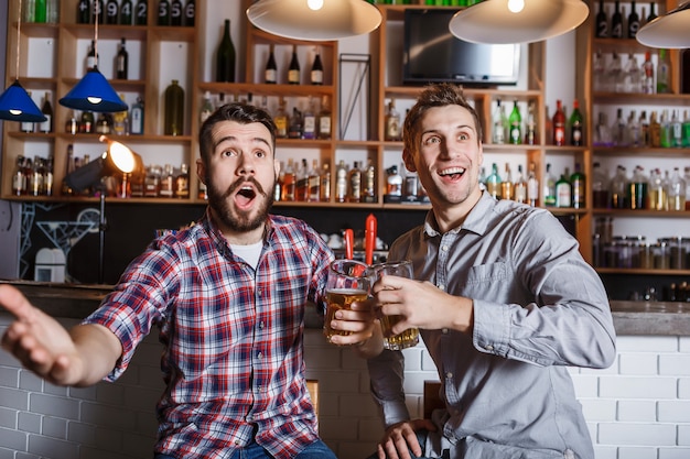 Free photo young people with beer watching football in a bar