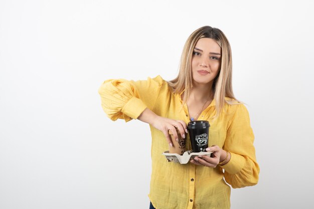 young person holding cups of coffee on white background.