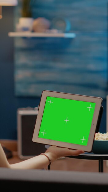 Young person looking at tablet with horizontal green screen background sitting in living room on couch. Woman using chroma key with isolated copy space for mockup template and copy space