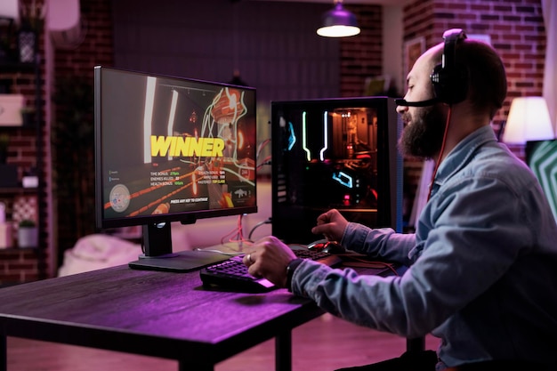 コンピューターでアクションビデオゲームに勝ち、オンラインゲーム選手権をプレイする若者。現代のコンピューターでのRPGトーナメントに満足し、ゲームプレイの勝利を祝う男性プレーヤー。