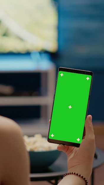 Free photo young person with vertical green screen display on smartphone