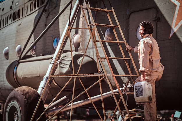 Young pilot makes a stop to refuel his cargo airplane using stairs. It's bright, sunny day.