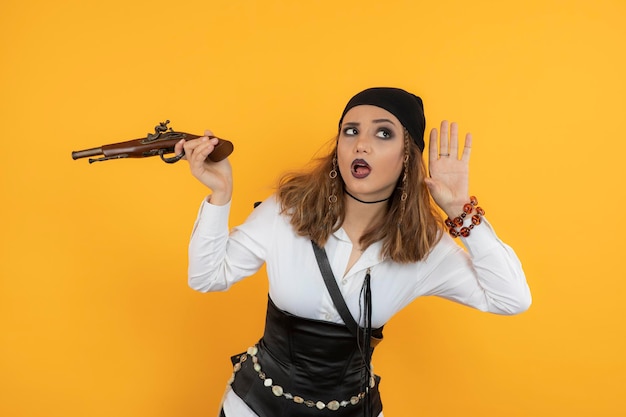 Free photo young pirate girl holding gun and trying to hear. high quality photo