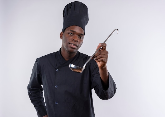 Free photo young pleased afro-american cook in chef uniform holds ladle out on white  with copy space