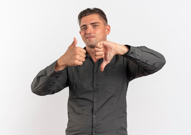 Young pleased blonde handsome man thumbs up and thumbs down isolated on white background with copy space