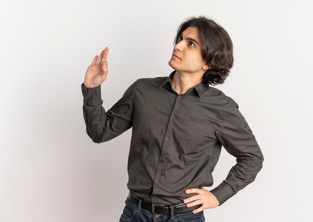 Young pleased handsome caucasian man looks at side and gestures ok hand sign isolated on white background with copy space