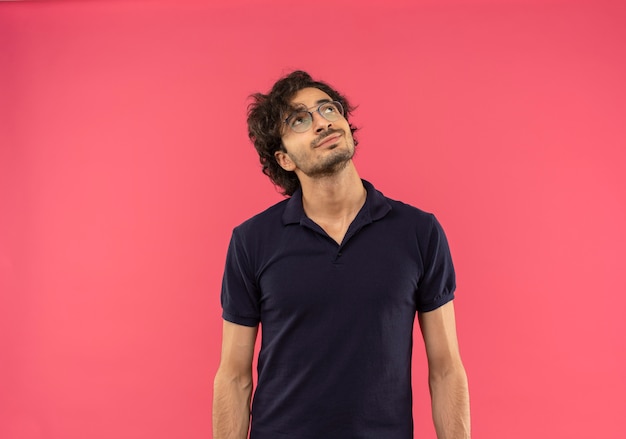 광학 안경 검은 셔츠에 젊은 기쁘게 남자는 분홍색 벽에 고립 조회