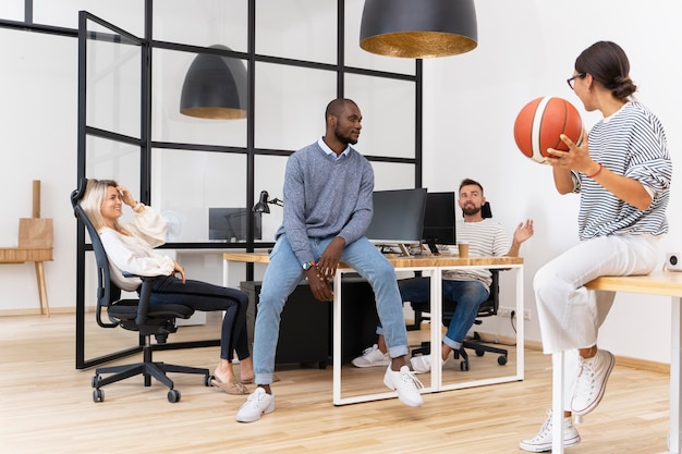 Young pleople playing with ball in office