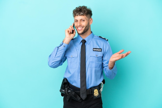 若い警察のブロンドの男は、誰かと携帯電話との会話を維持している青い背景に白を分離しました
