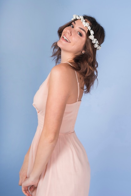 Young positive brunette lady in pink dress with beautiful flower wreath