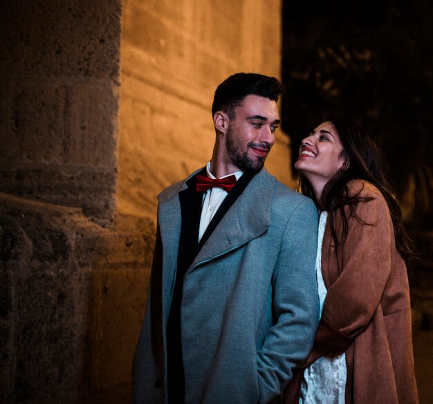 Young positive guy near cheerful attractive lady on street in evening