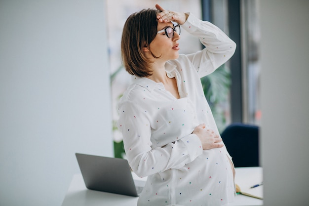 Free photo young pregnant business woman at the office