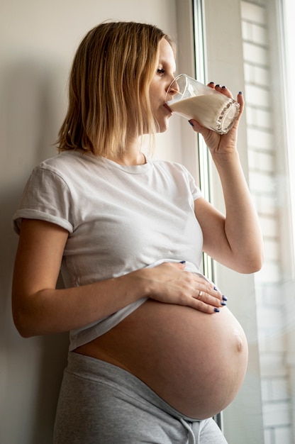 Foto gratuita latte alimentare della giovane donna incinta