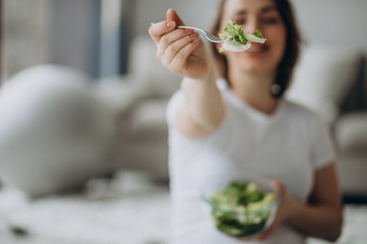 Free Photo young pregnant woman eating salad at home