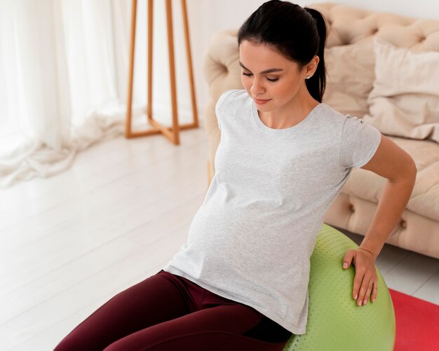 Young pregnant woman exercising on fitness ball