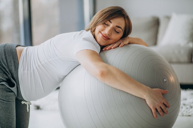 Young pregnant woman exercising yoga with fit ball at home