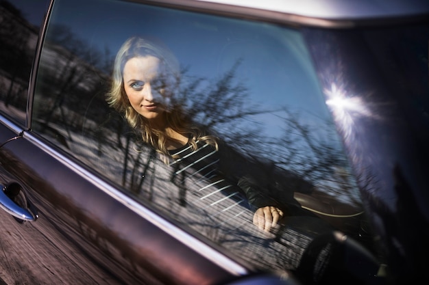 Молодая беременная женщина, глядя через прозрачное окно автомобиля