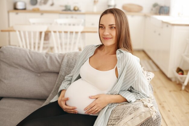 Молодая беременная женщина позирует в помещении
