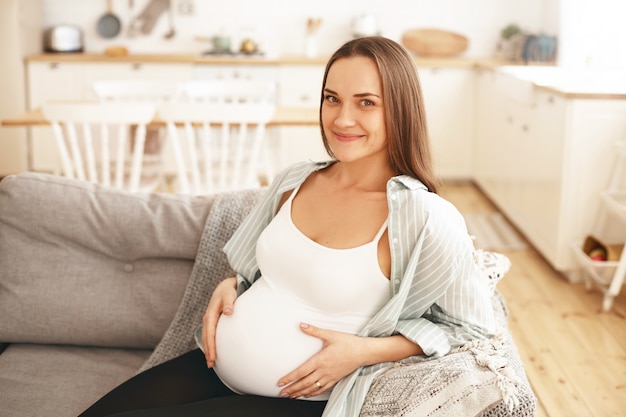 屋内でポーズをとる若い妊婦