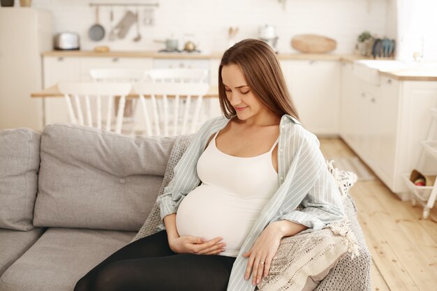 屋内でポーズをとる若い妊婦