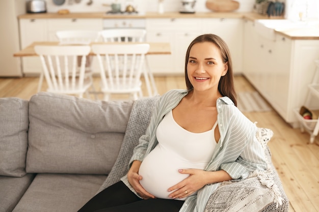 屋内でポーズをとる若い妊婦