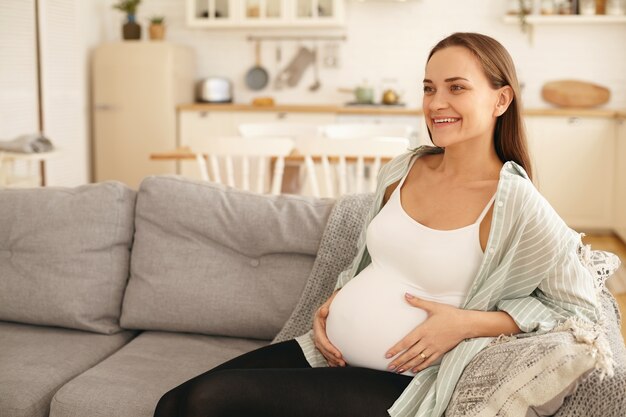 Молодая беременная женщина позирует в помещении