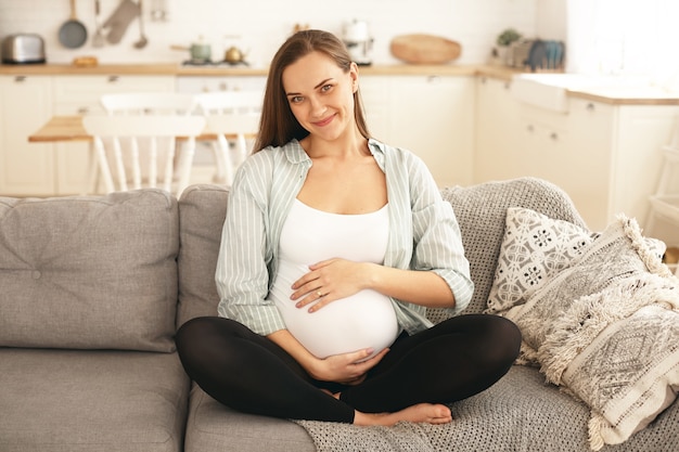 Бесплатное фото Молодая беременная женщина позирует в помещении