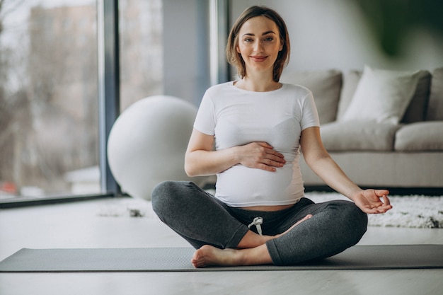 Young pregnant woman practicing yoga at home