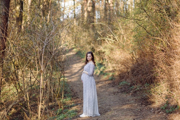 Young pregnant woman relaxing in park outdoors