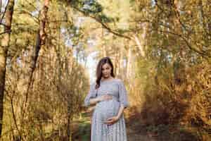 Free photo young pregnant woman relaxing in park outdoors