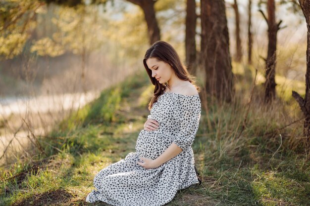 Young pregnant woman relaxing in park outdoors