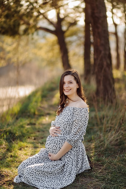 Young pregnant woman relaxing in park outdoors