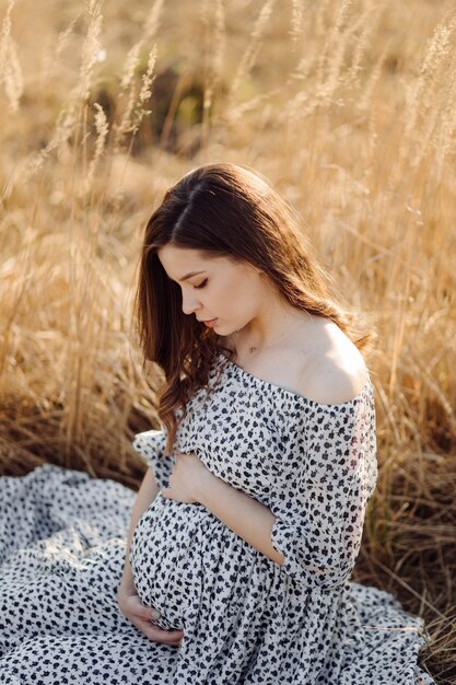 Young pregnant woman relaxing in park outdoors