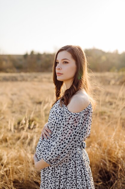 Young pregnant woman relaxing in park outdoors