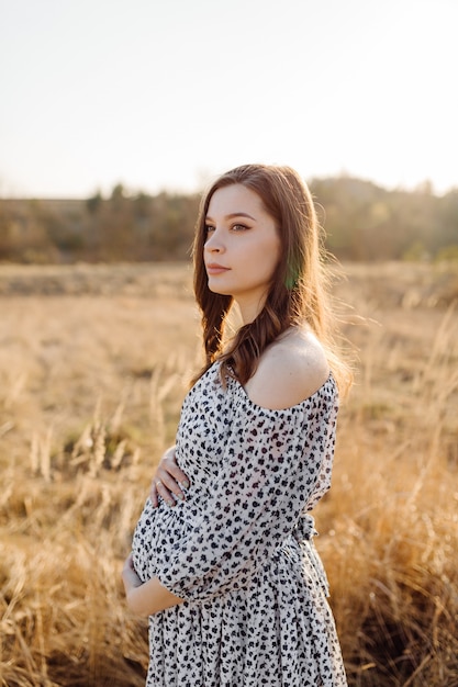 Young pregnant woman relaxing in park outdoors