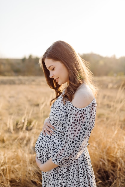 Young pregnant woman relaxing in park outdoors