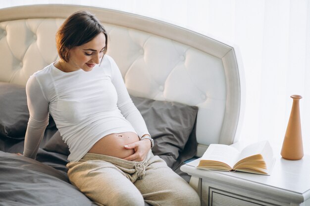 Young pregnant woman sitting in bedroom