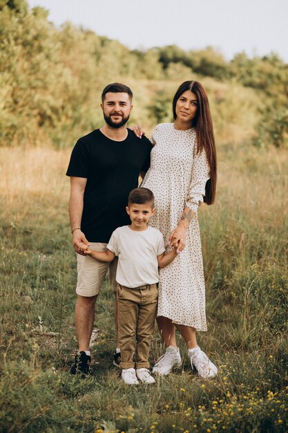 Young pregnant woman with husband and son in a forest