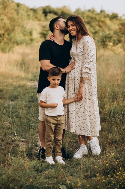 Молодая беременная женщина с мужем и сыном в лесу