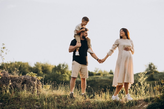 Young pregnant woman with husband and son in a forest